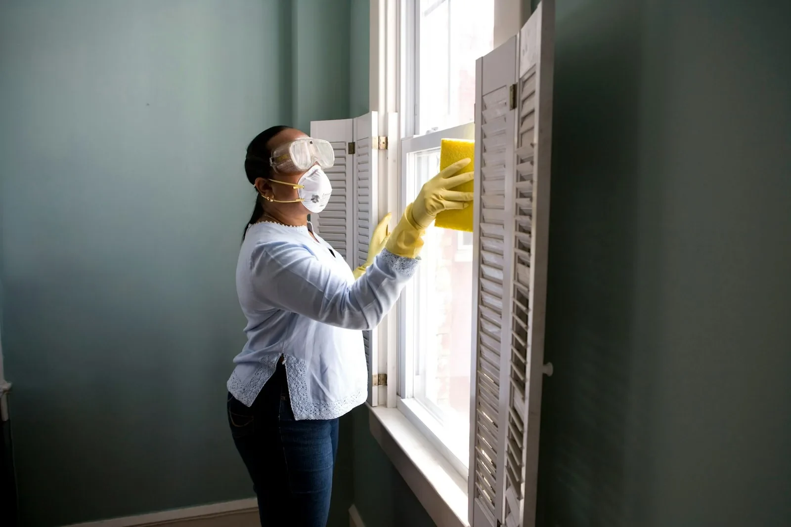 A professional cleaner carefully refreshing a bright window
